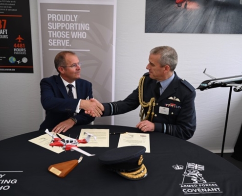 Two men shaking hands, one in RAF uniform, one in a blue suit