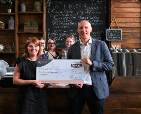 Five people with large cheque in a cafe