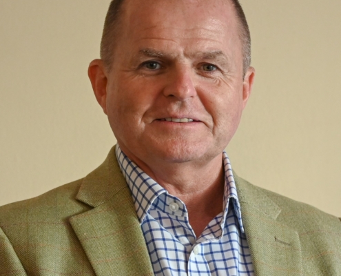 Roger Wyness wearing tan jacket and blue and white checked shirt