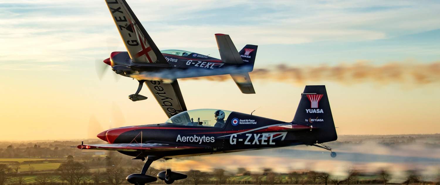 Two Extra 300 aircraft in flight against a sunset